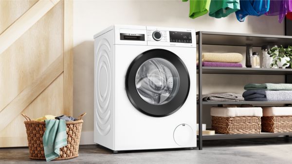A white washing machine sitting on top of a wooden floor