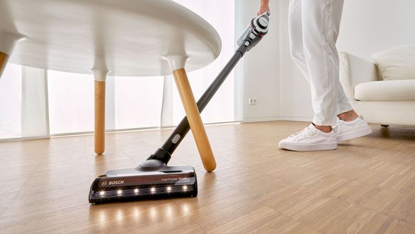 Woman operating vacuum on hardwood floor.
