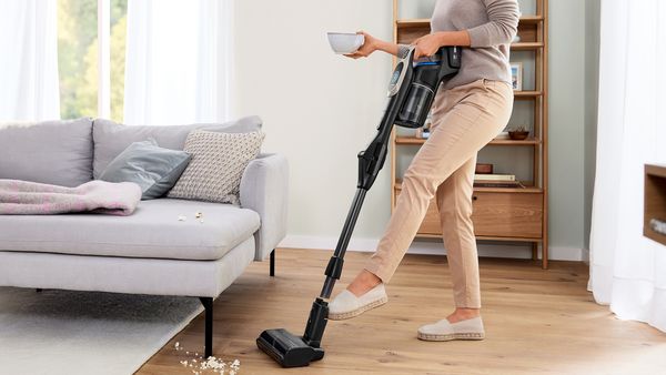 Femme tenant un bol d'une main et l'Unlimited de l'autre, activant avec son pied le système de déverrouillage au pied.