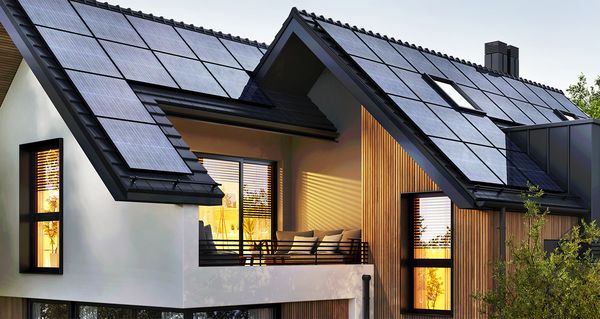 Beleuchtetes Haus mit Solarpanelen bei Dunkelheit