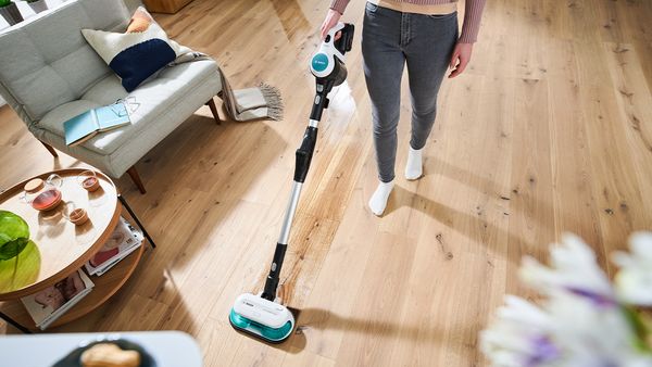 Schnell aufräumen und putzen: Eine Person reinigt einen Holzboden mit dem Unlimited 7 ProHygienic Aqua von Bosch.