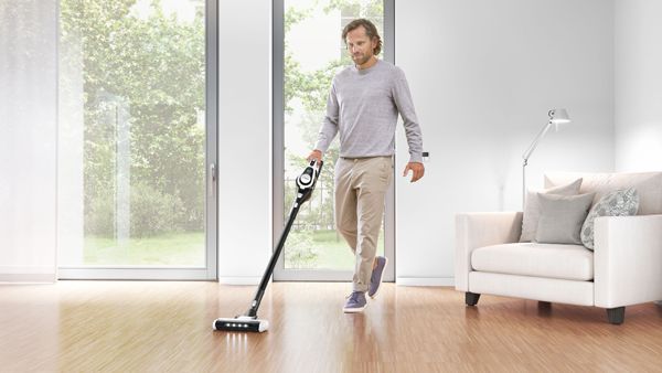 Man cleaning hardwood floor with vacuum cleaner.