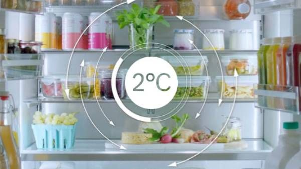 Un smartphone affichant le contenu d'un réfrigérateur-congélateur via l'application Home Connect. En arrière-plan, le réfrigérateur-congélateur ouvert est visible dans la cuisine et laisse entrevoir ce qu'est la gestion pratique et moderne des aliments.