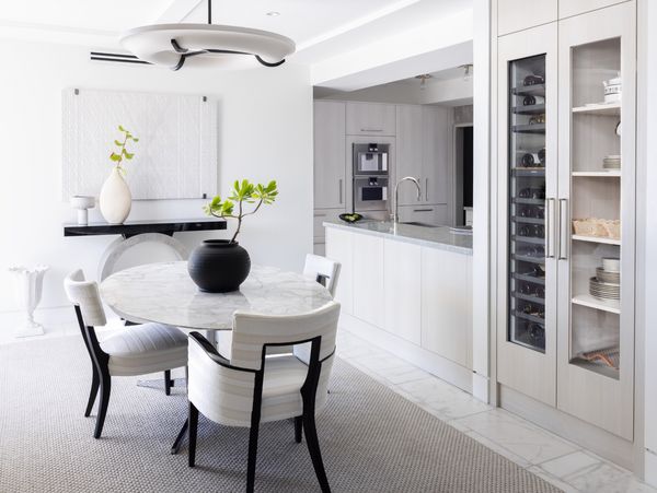 The cleanly designed dining room in Jonathan Savage’s stylish Ibis Isle condominium in Palm Beach, with a Gaggenau wine cabinet and the kitchen full of Gaggenau appliances.