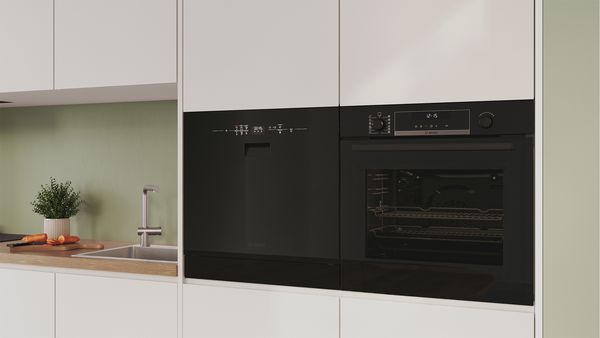 A small built-in dishwasher with an open door and a full rack.