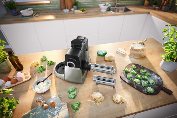 Cucina contatore con pastaio, ingredienti freschi e pianta in vaso. 