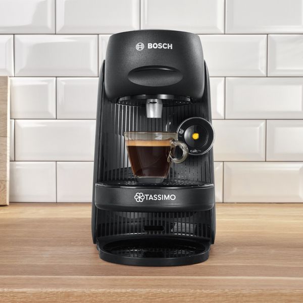 Tassimo coffee maker with a steaming cup of coffee placed on top, ready to enjoy.  