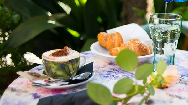 A flowery tablecloth featuring vibrant floral patterns, complemented by a cappuccino cup placed on the table.  