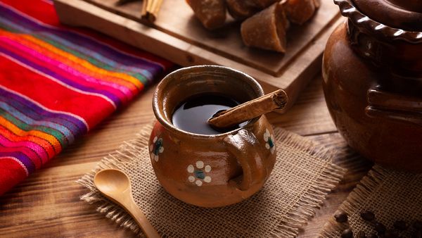 Mexican café de olla in a ceramic mug, garnished with cinnamon sticks for a traditional touch.