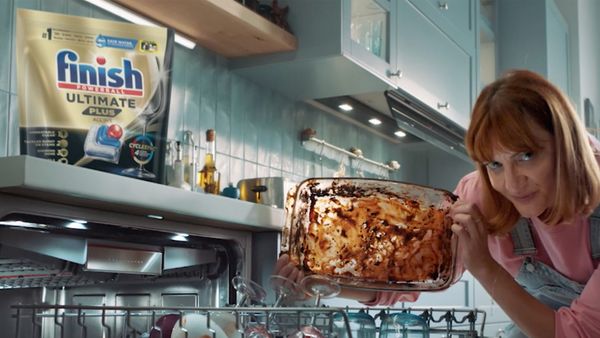 Woman showing dirty tray in fron of dishwasher