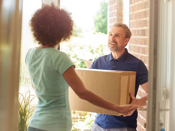 Delivery man handing parcel to a woman in doorway