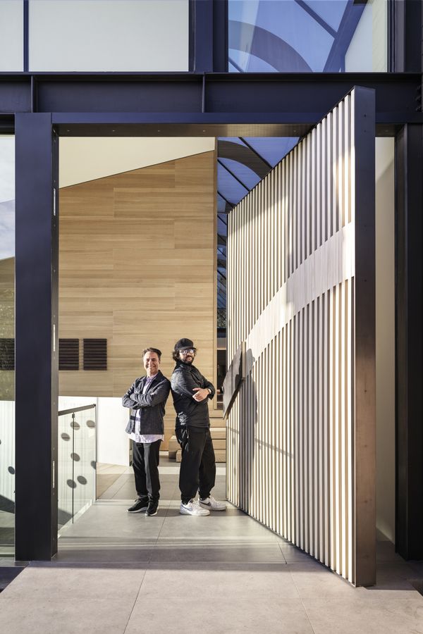 A candid photo of César Giraldo and Sean Balakhani standing in front of the very large front door