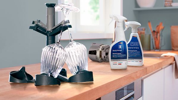 Wooden kitchen worktop with cleaning products and a glass holder.