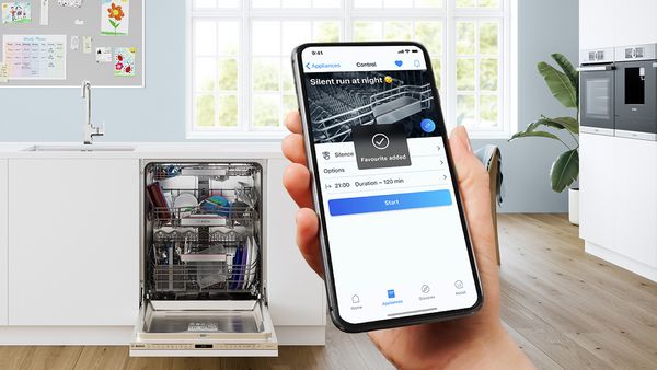 A hand holds a smartphone, open to an app that provides expert advice on the Bosch dishwasher visible in the background.