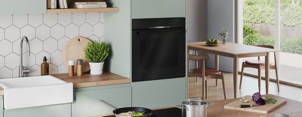 Una cocina luminosa y moderna, con una olla y una sartén en la placa y dos hornos al fondo.Una cocina luminosa y moderna, con una olla y una sartén en la placa y dos hornos al fondo.