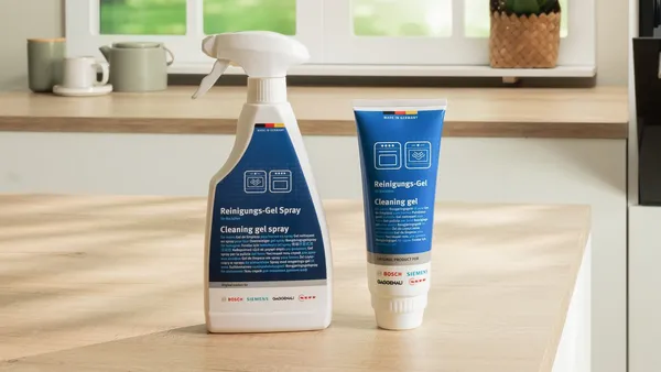 Cleaning spray bottle and gel tube on a kitchen counter with blurred background.