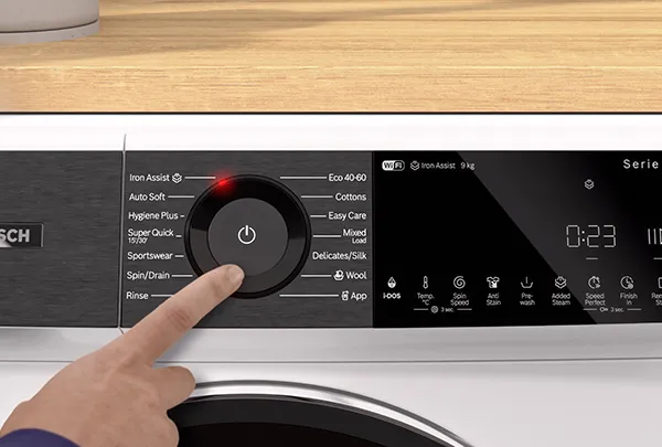 יש של אדם לוחצת על כפתור במכונת כביסה של בוש סדרה 8