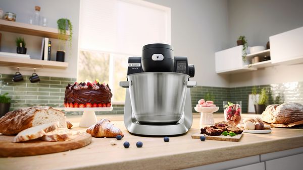 A blender rests on a kitchen counter alongside various food items, showcasing results of  blending and cooking.