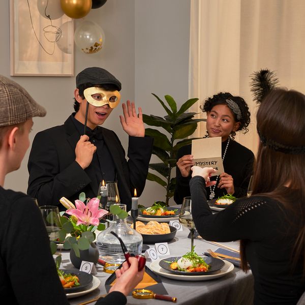 Amici che fanno una cena a tema con maschere e indizi