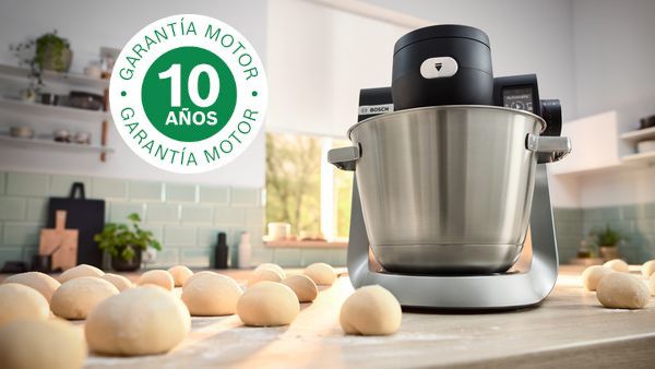  La imagen muestra un robot de cocina Serie 6 en la encimera de la cocina, junto a numerosas bolas de masa y el logotipo de 10 años de garantía superpuesto.