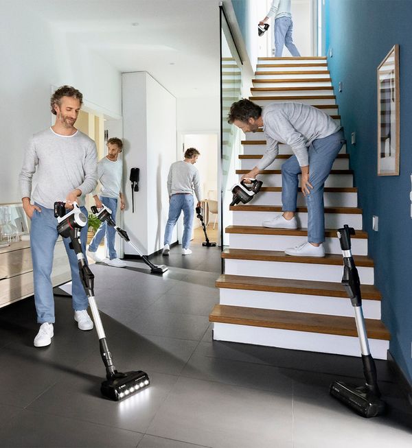 Woman cleans the kitchen floor with a flexible cordless Unlimited vacuum.