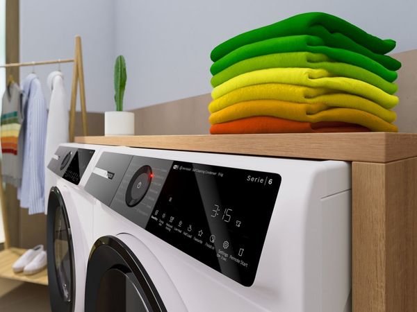 wasmachine en droger naast elkaar met stapel kleding bovenop