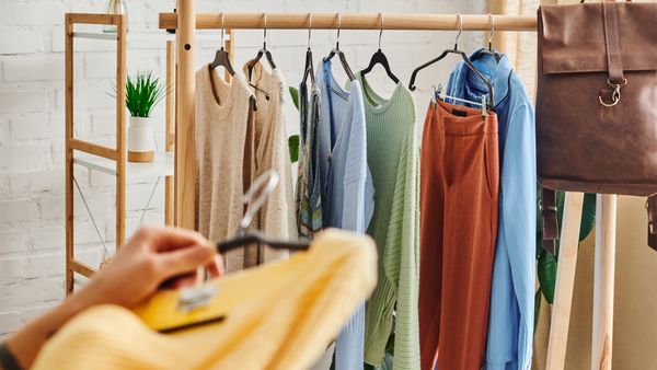 A woman examines clothing on a rack while holding a bag, showcasing her shopping experience in a retail environment.