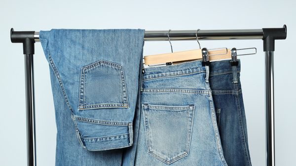 A pair of blue jeans neatly hanging on a clothes rack, showcasing their casual style and denim texture.