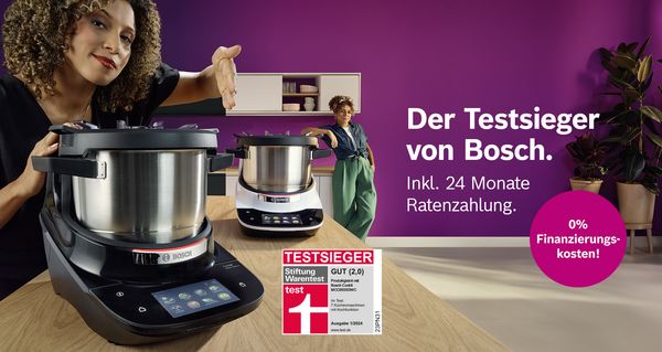 Der Bosch Cookit Testsieger mit 24 Monaten Ratenzahlung ab 1.399 €. Zwei Personen präsentieren die Küchenmaschine vor lila Hintergrund, und ein lila Hinweis weist auf 0% Finanzierung hin.