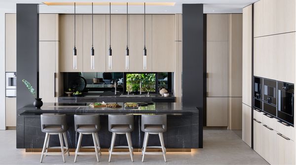 The open kitchen of the Dana Point home, with sleek black marble countertops set against neutral earth tones. 