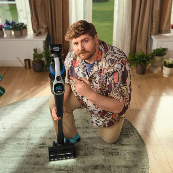 A bearded man holding an Unlimited 10 vacuum cleaner