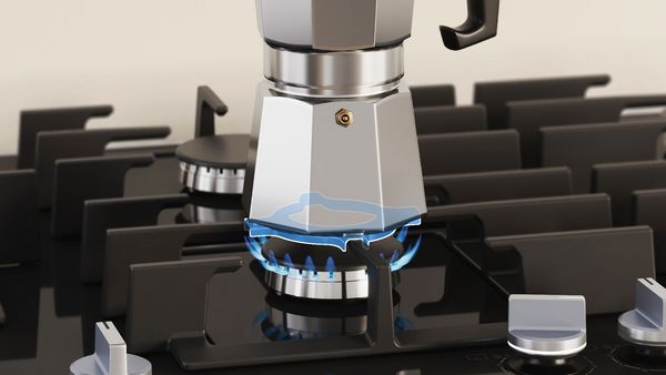 Une machine à espresso est posée sur la plaque de cuisson au gaz.