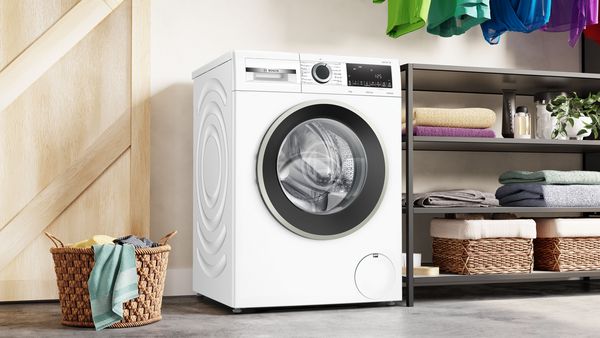 A closeup of the control panel and drum full of colourful laundry.