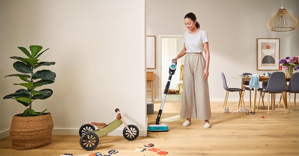 Person using Bosch Aqua vacuum in messy living area