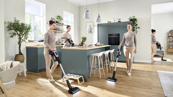 Una aspiradora sin cable Unlimited 9 sobre suelo duro, junto a ella un cojín de asiento y el logotipo de 10 años de garantía del motor.