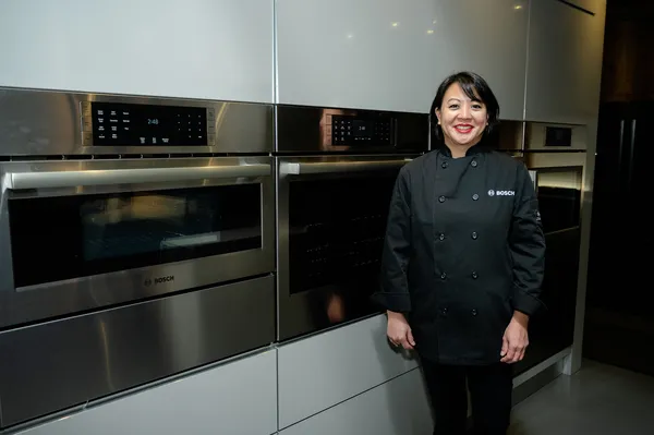 Professional chef stands next to Bosch kitchen appliances, showcasing modern features and sleek design.