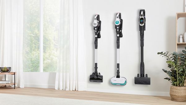 Drei Akku-Staubsauger der Bosch Unlimited Modellreihe hängen nebeneinander an der Wand.