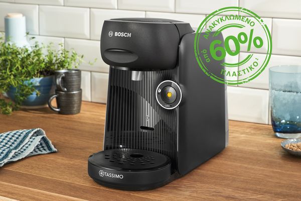 Η μηχανή ροφημάτων TASSIMO FINESSE friendly πάνω σε έναν πάγκο κουζίνας. Δίπλα της ένα σήμα για 60% ανακυκλωμένο πλαστικό.
