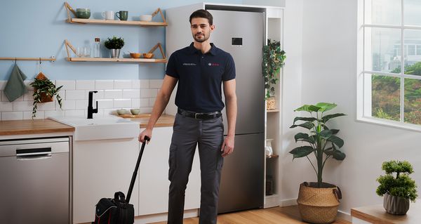 Bosch tekniker i moderne køkken med værktøjstaske.     