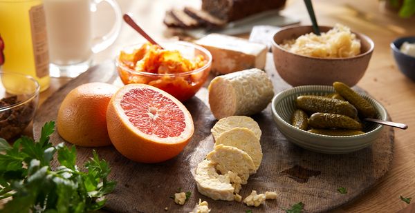 Auf einem runden Küchenbrett sind verschiedene darmfreundliche Lebensmittel arrangiert, die das Mirkobiom stärken können.