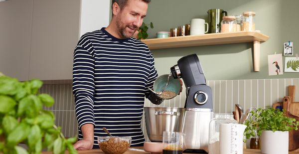 Ein Mann verarbeitet mit der Bosch Küchenmaschine Serie 6 Lebensmittel in einer Küche, um sich gesund zu ernähren und sein Mikrobiom zu stärken.