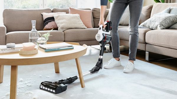 Person using a vacuum with bendable tube to clean under table