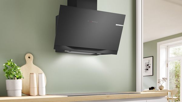 A black wall mounted hood in a bright modern kitchen.