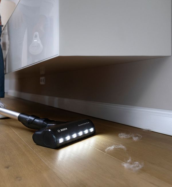 A person vacuums a wooden floor, demonstrating effective cleaning techniques in a tidy living space.