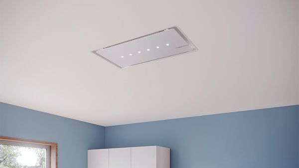 A modern ceiling-mounted range hood with LED lights installed in a clean, blue-walled kitchen.