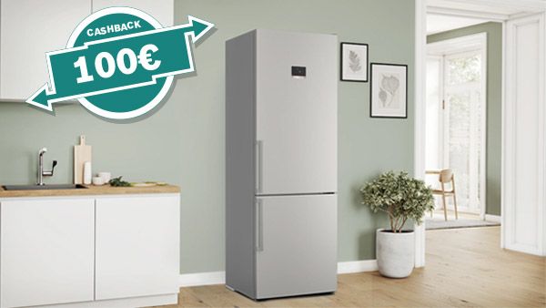 Un frigorifero moderno in acciaio inox in una cucina elegante, con un'offerta di cashback di 100&euro;. Spazio luminoso e accogliente con piante. 