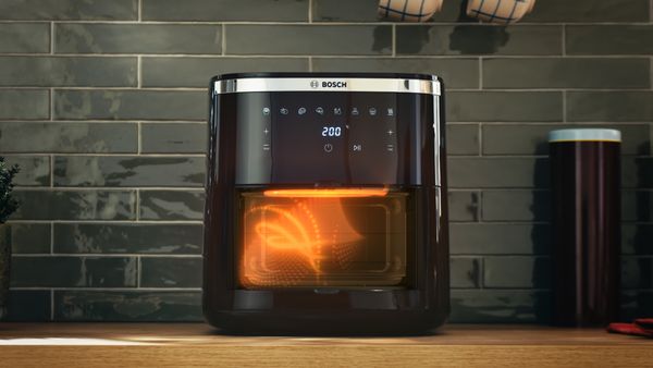 Friggitrice ad aria Bosch in funzione con camera di cottura illuminata per una cottura uniforme ed efficiente