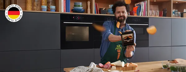 אדם חותך ירקות ותפוחי אדמה שעפים לכל עבר ומאחוריו תנור בנוי של בוש