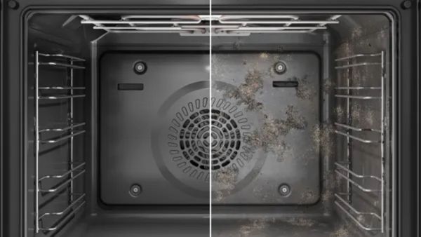 Vuil oven interieur met kruimels en puin verspreid over de planken en ventilator.