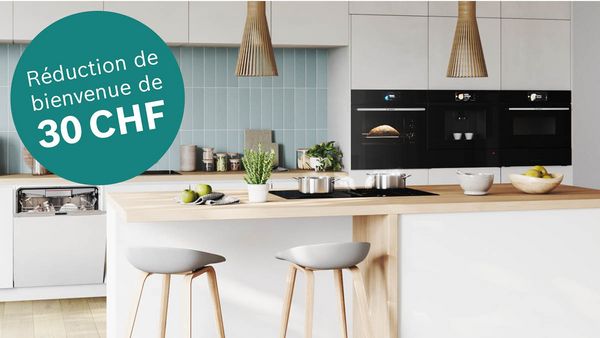 Cuisine moderne avec plan de travail en bois, électroménagers et panneau annonçant une réduction de 30 CHF.
